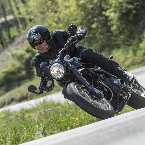 A black Ducati Scrambler Café Racer 2017 being ridden on a rural road
